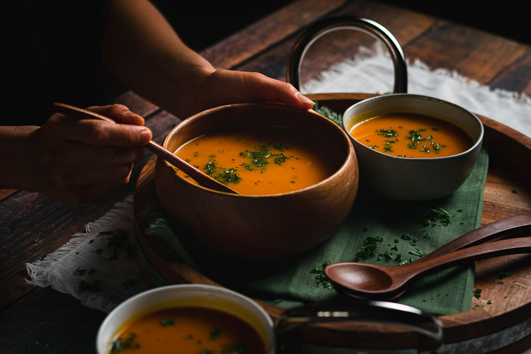 someone reaching for a spoonful of vegan kabocha soup