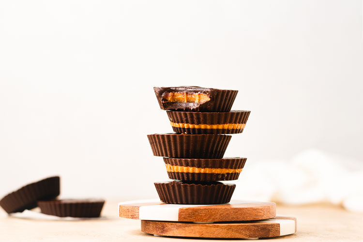 homemade peanut butter cups stacked on top of each other with a bite taken out of the top pb cup