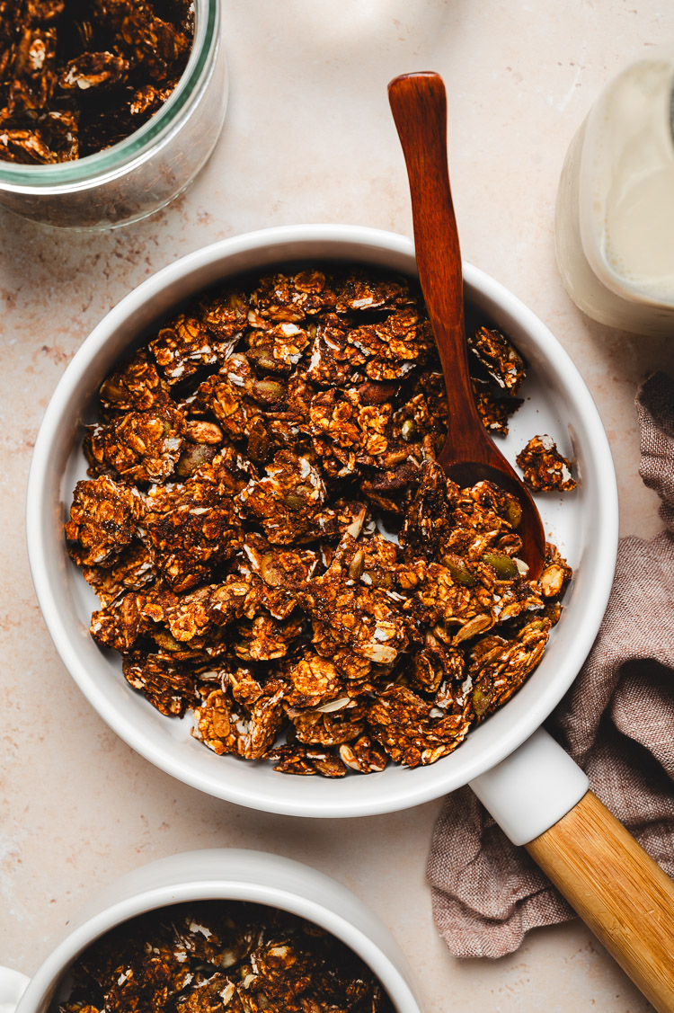 flatlay of date sweetened granola in a bowl with spoon, milk bottle on the side