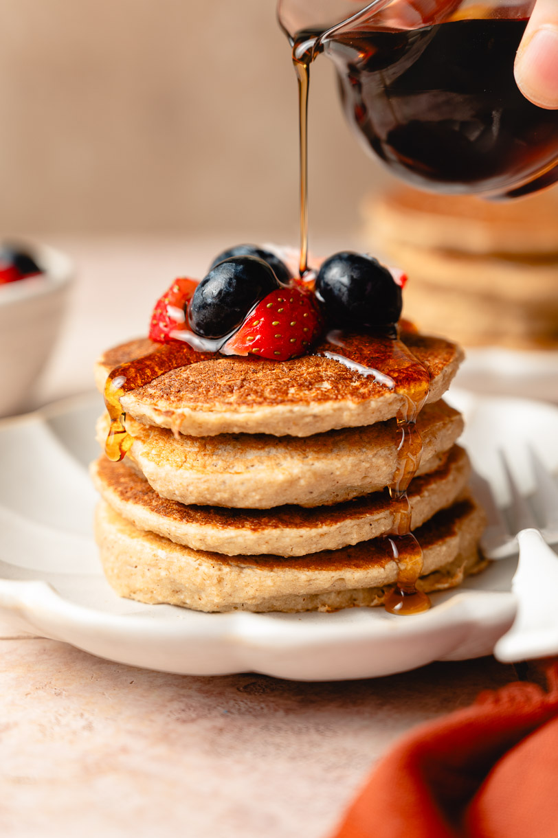 stack of tofu banana pancakes with maple syrup poured on top